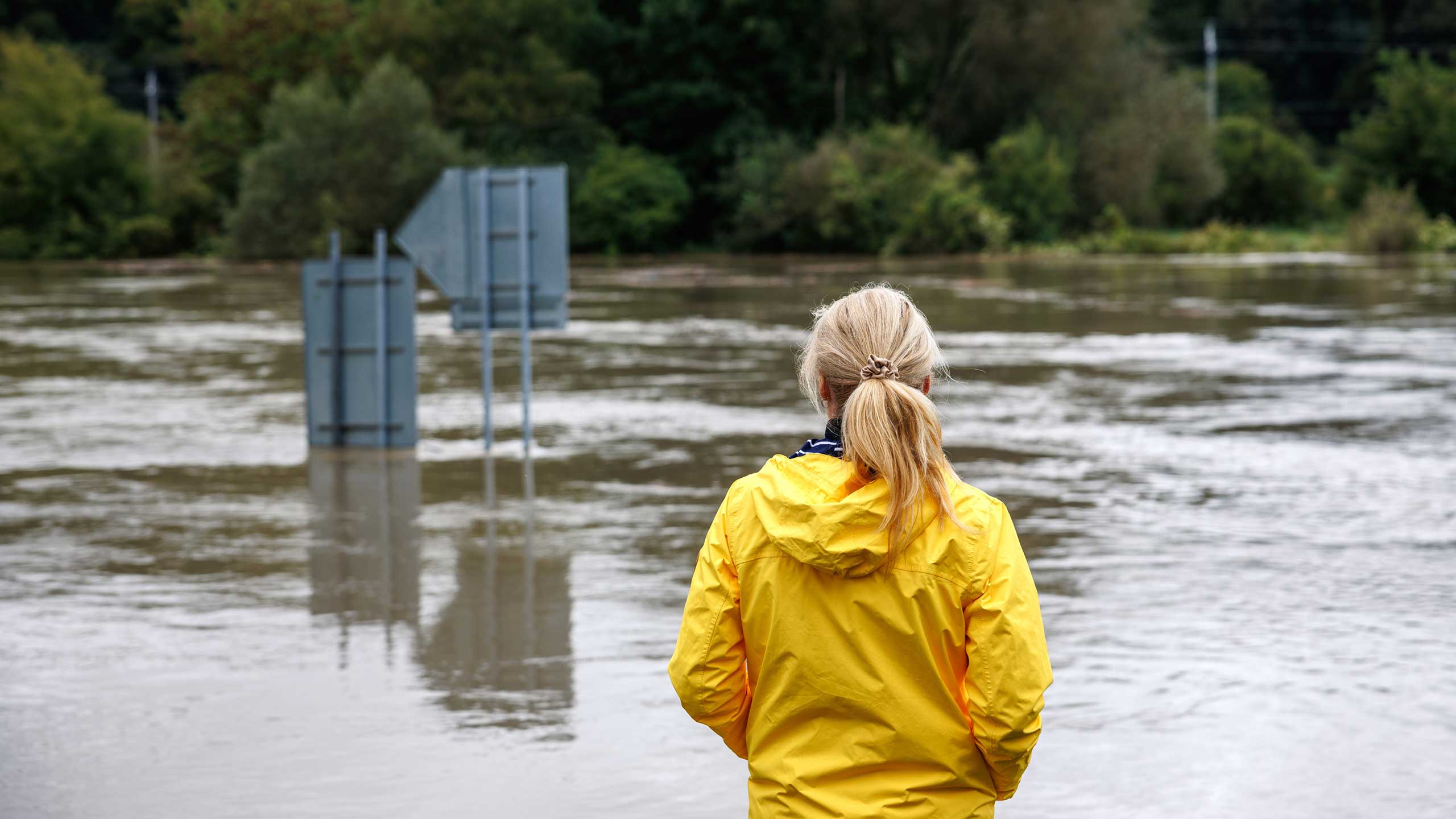 Woman in yellow rain jacket overlooking flood zone